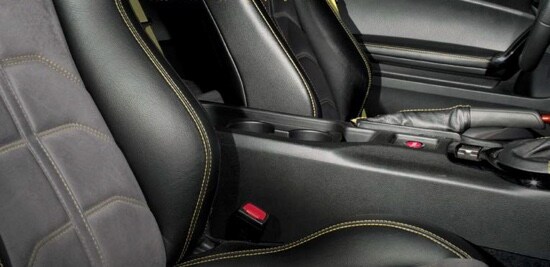 The interior of a car with black leather seats and red stitching.