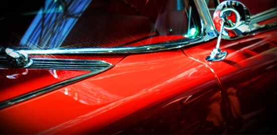 The side-view mirror of a red classic car.
